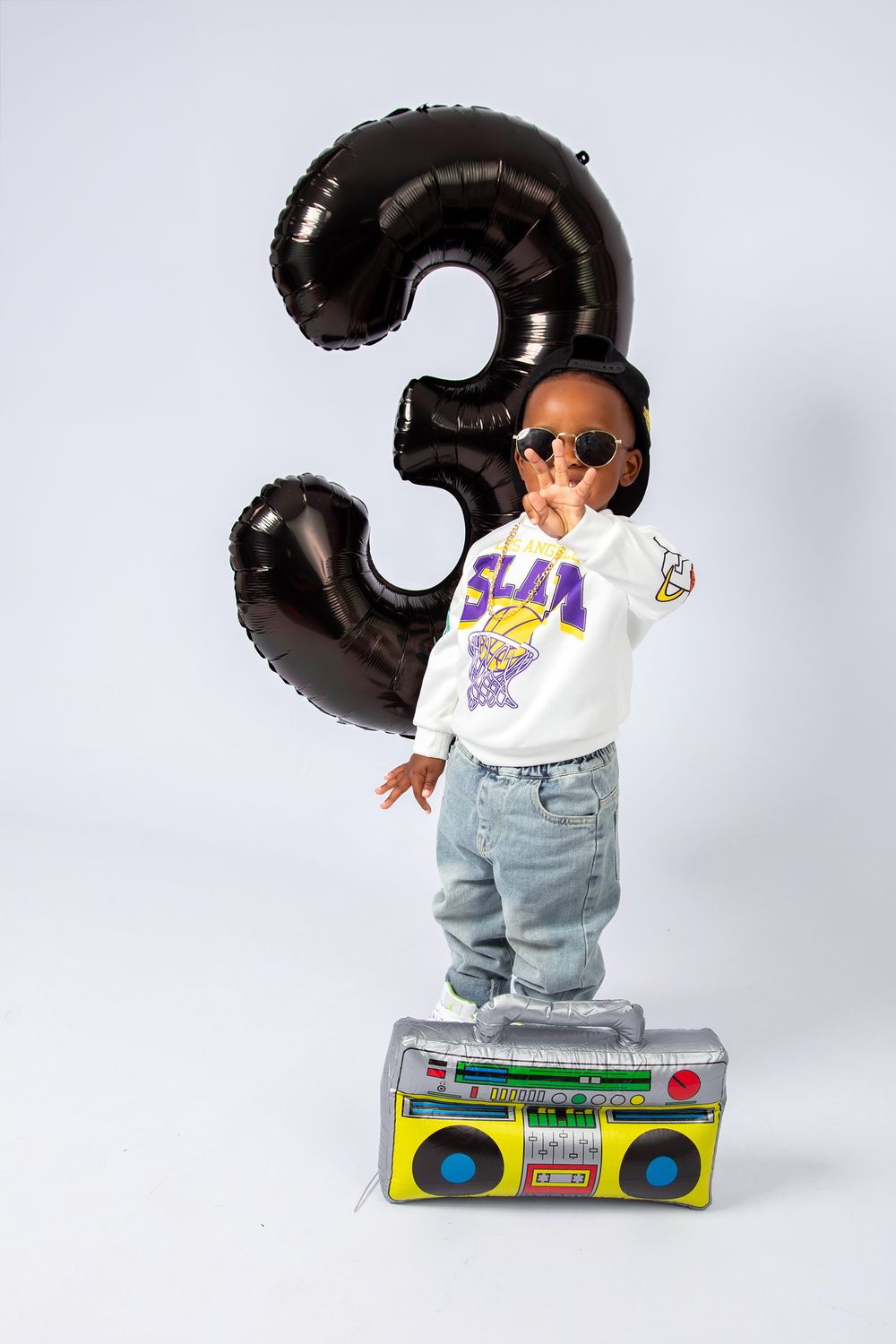 Birthday number 3 balloon floats behind a person in sunglasses dancing on a retro boombox in a casual hip-hop style outfit.