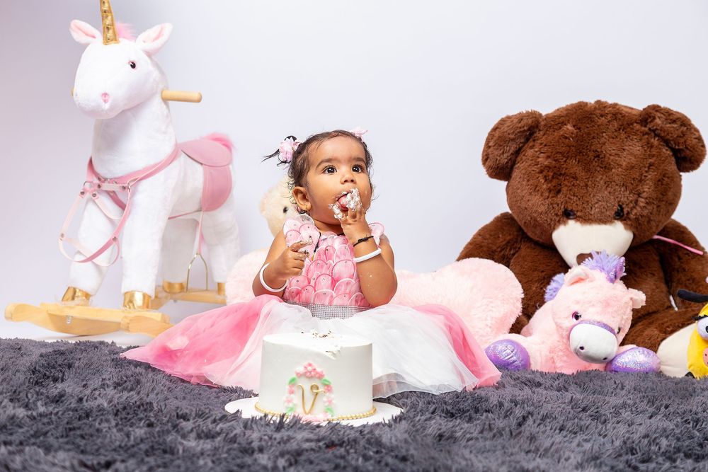 White unicorn plush toy with colorful stuffed animals arranged on grey plush carpet background.