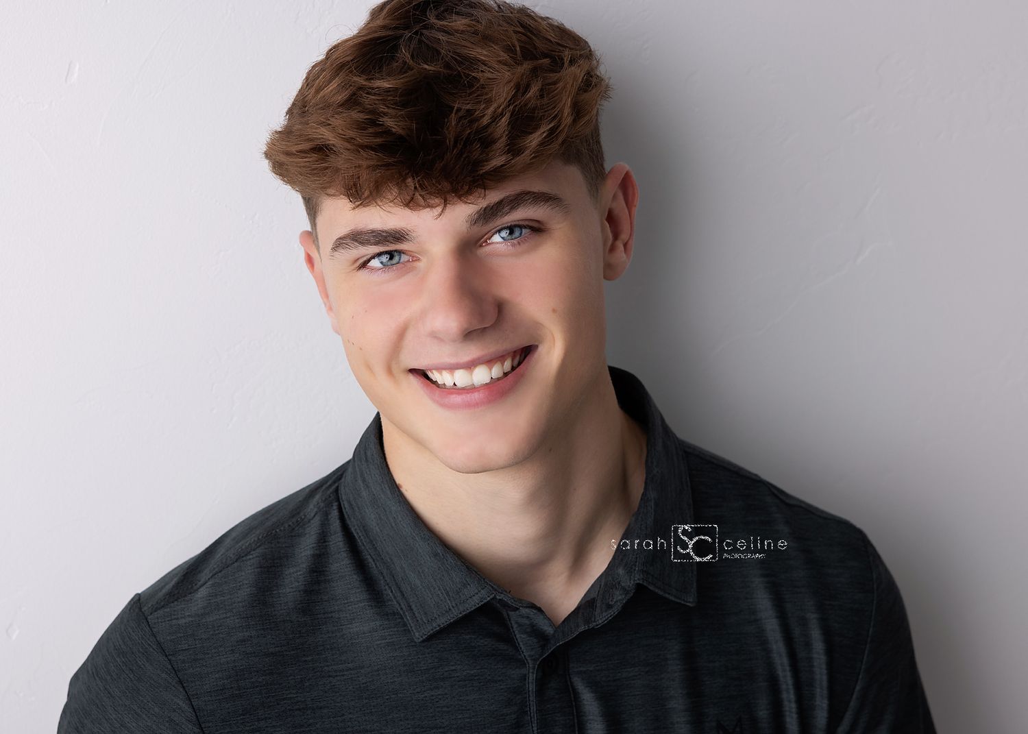 Professional headshot portrait against a gray background wearing a dark colored shirt.