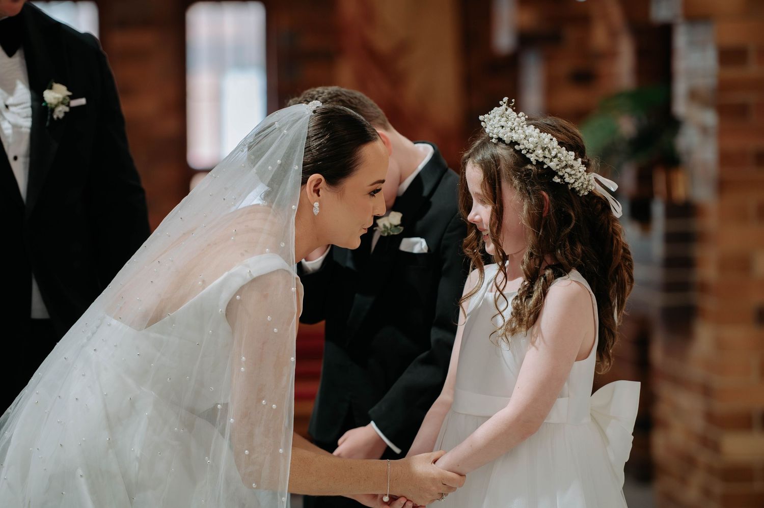 A tender moment shared during a wedding ceremony in a rustic brick church setting.