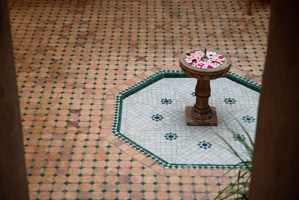 Fontaine centrale entourée de mosaïques marocaines, élément apaisant de la cour intérieure.