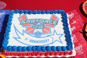 A white frosted birthday cake with blue trim features an ArieForce One anniversary logo and design on top.
