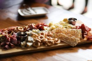 A rustic charcuterie board with meats, cheeses, olives and crackers arranged on wooden serving platter.