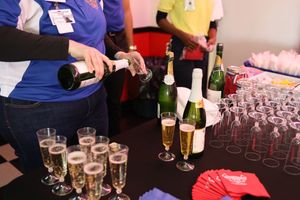 Champagne bottles and glasses being prepared on a bar at an event service setup.