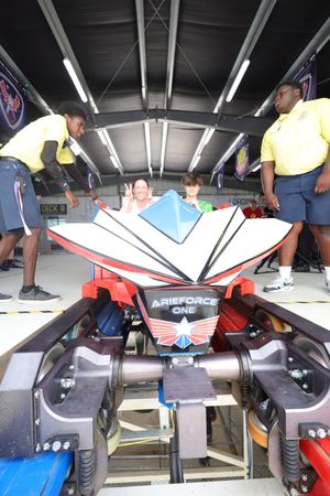 People exploring inside of a seated flight simulator located in what appears to be an educational facility.