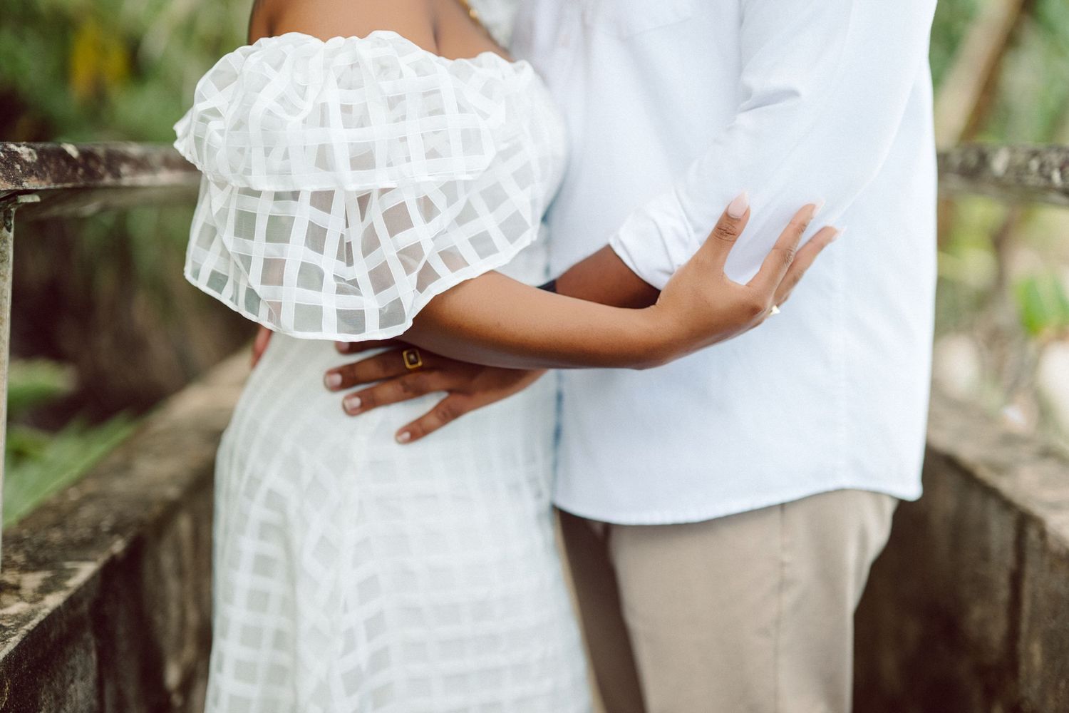A couple embraces in white attire during an intimate outdoor photo session.