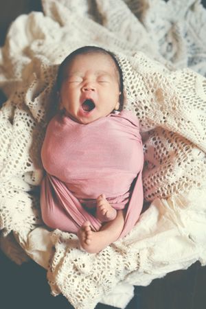 A series of four newborn portraits in pink swaddle on cream colored lace fabric.