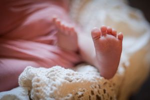 Close up photos of tiny newborn baby feet against a soft white blanket with delicate lace details.