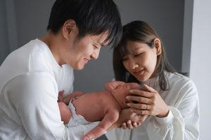New parents lovingly hold and gaze at their newborn baby in a tender home moment.