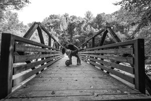 A black and white photograph of a wooden bridge walkway with two silhouettes standing in the middle.