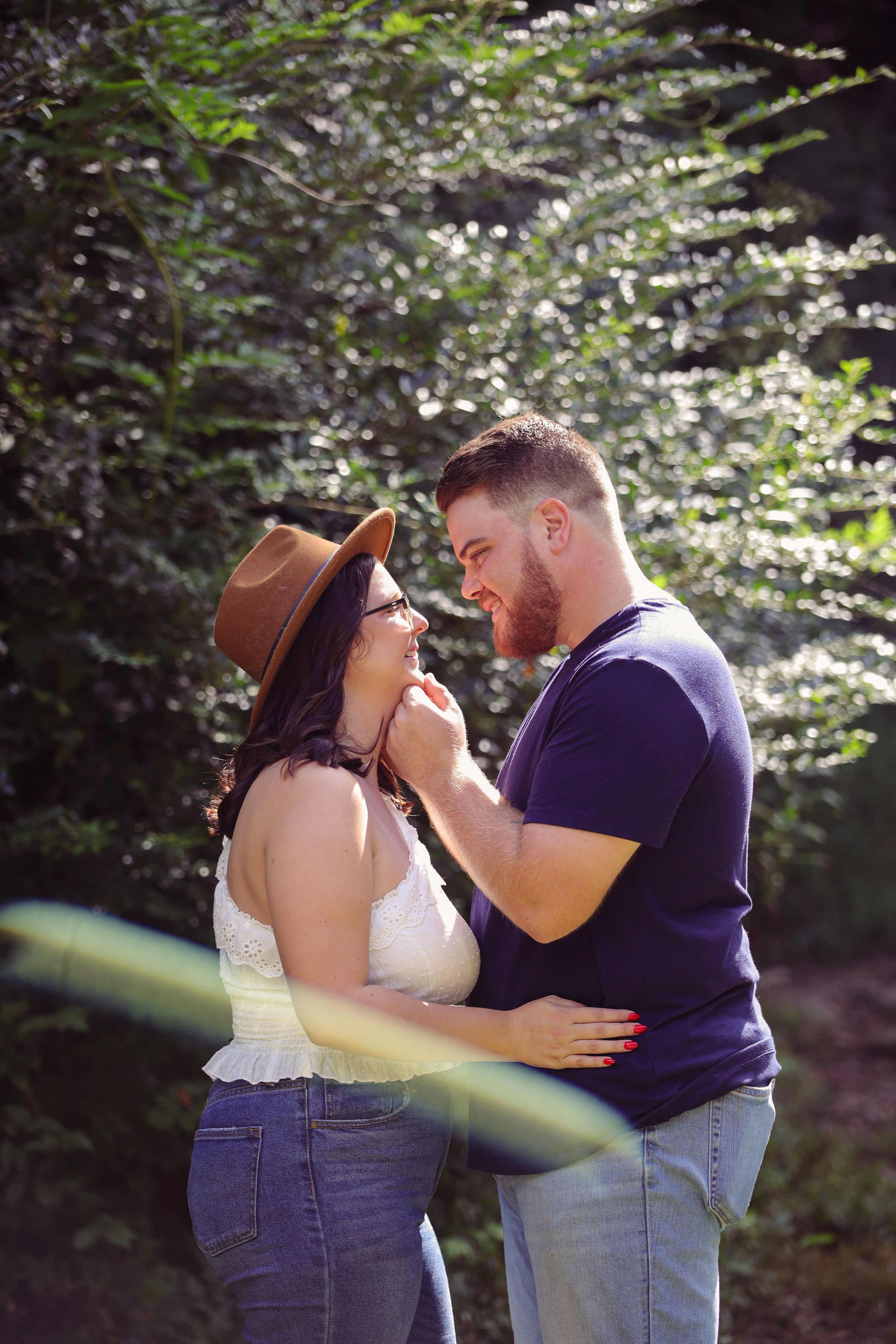 Row of four photos showing a romantic outdoor engagement session in a wooded setting with soft lighting and flowering trees.