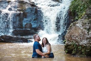 Picturesque engagement photoshoot by cascading waterfalls in the forest.