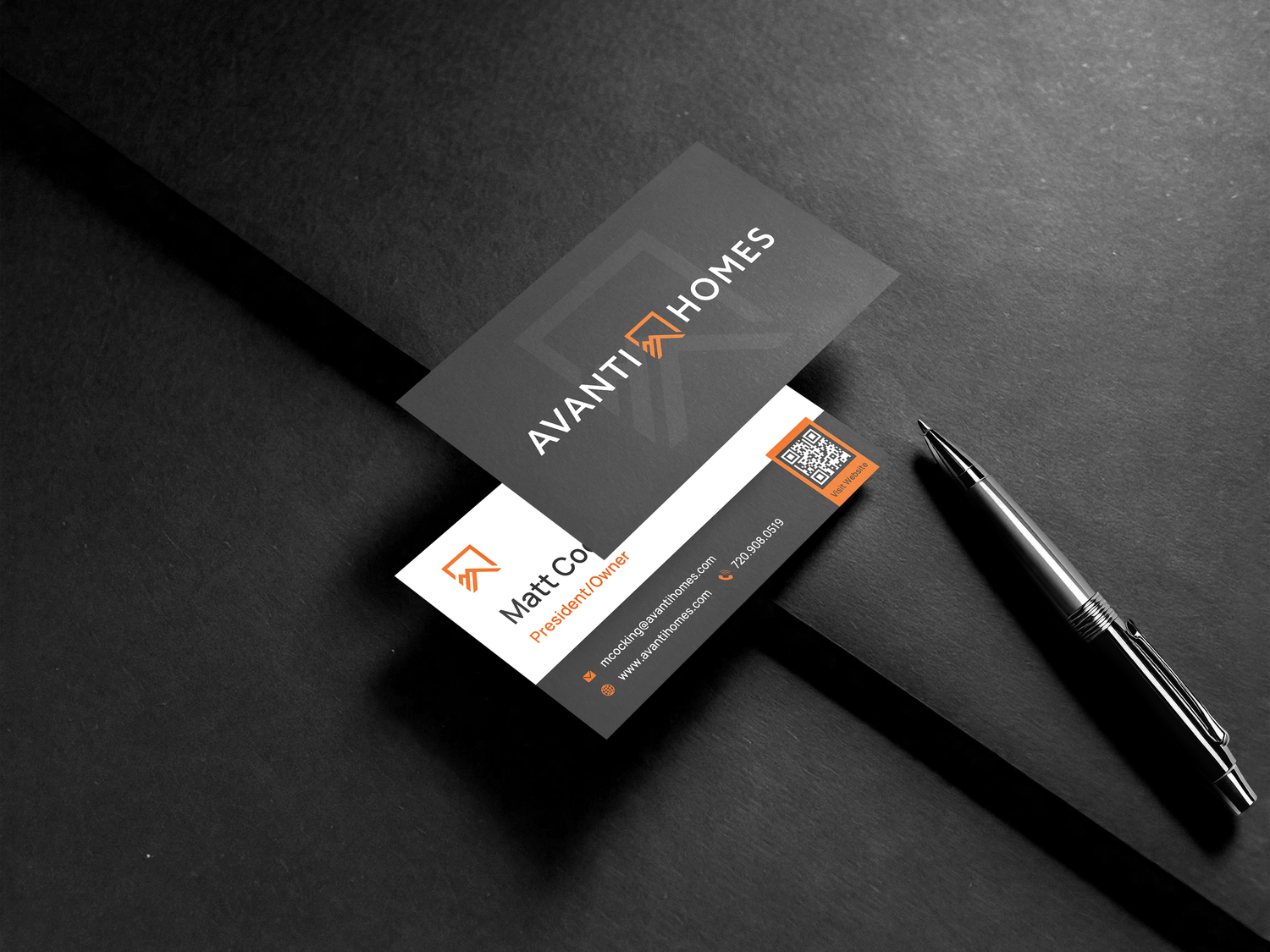 Modern business cards with Avanti Homes branding displayed on dark surface with a black pen.