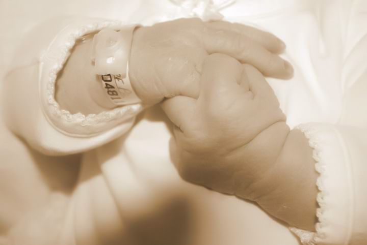 A close-up sepia photograph shows a tiny baby's foot next to delicate lace trimming.