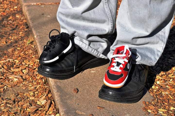 Person wearing mismatched sneakers with one black Nike Air Force 1 and one red and white sneaker on autumn ground.