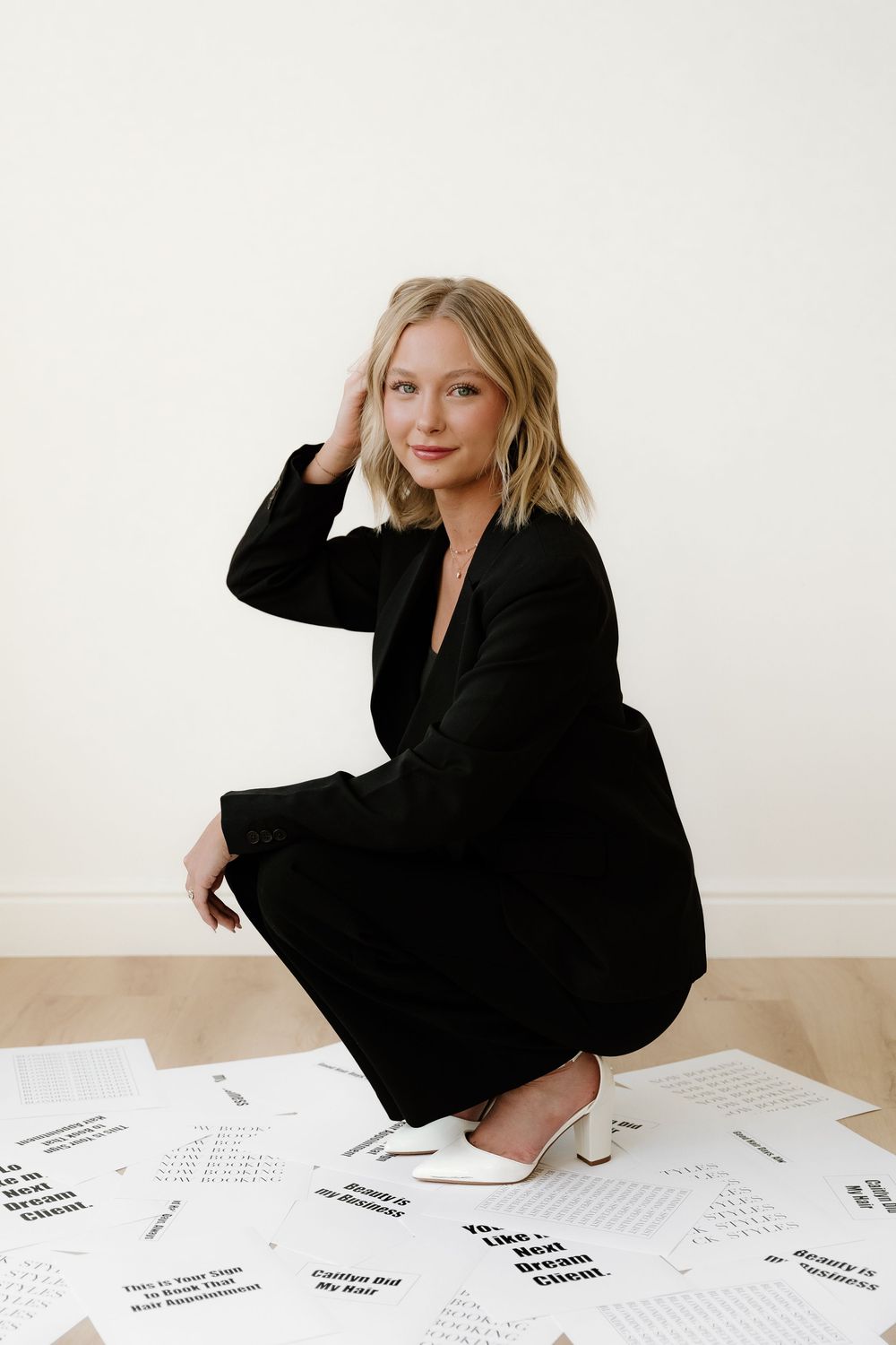 Elegant black dress outfit styled with papers scattered on wooden floor.