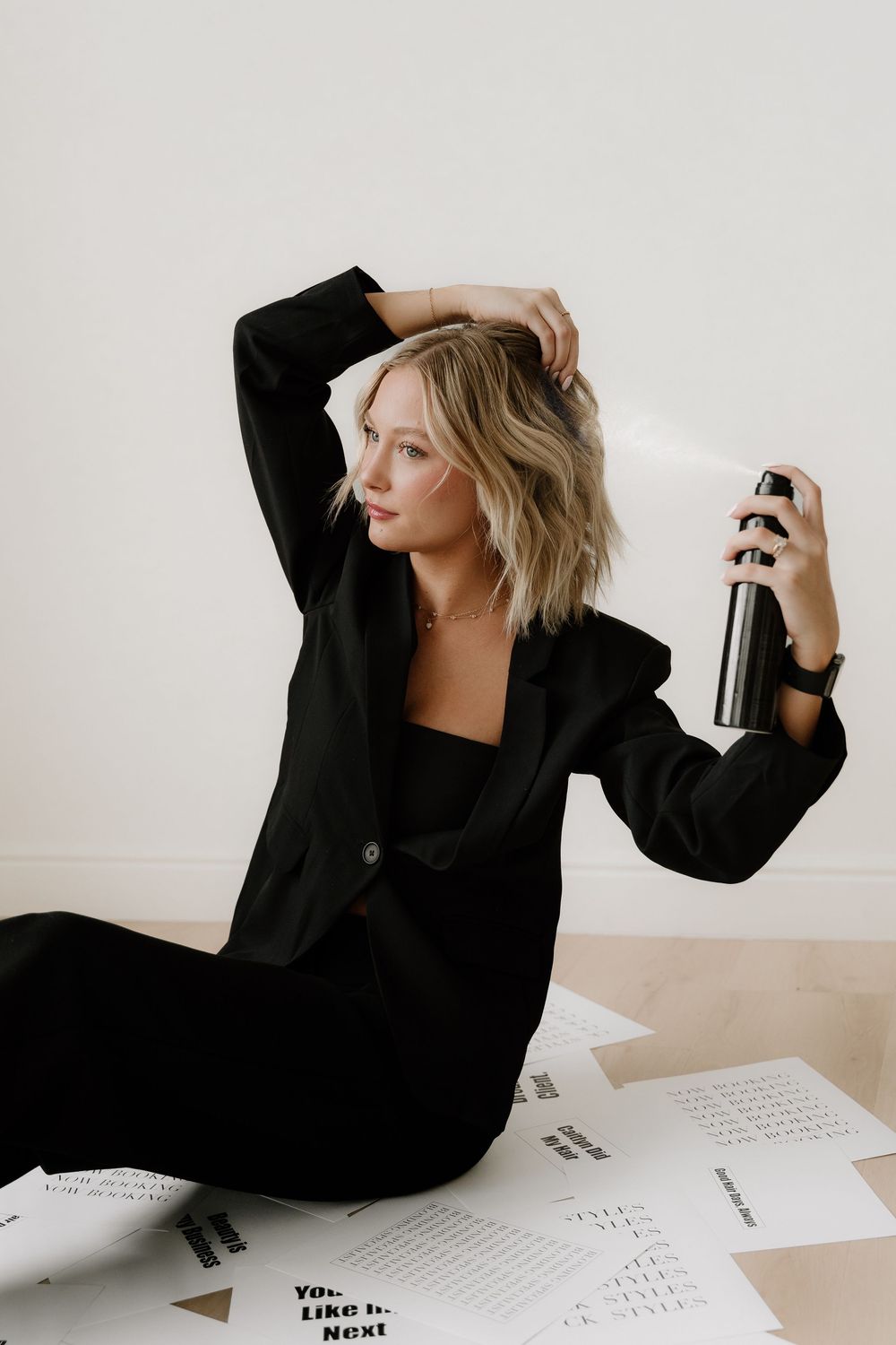 Artistic fashion scene with someone in a black blazer posing against a minimal white background.