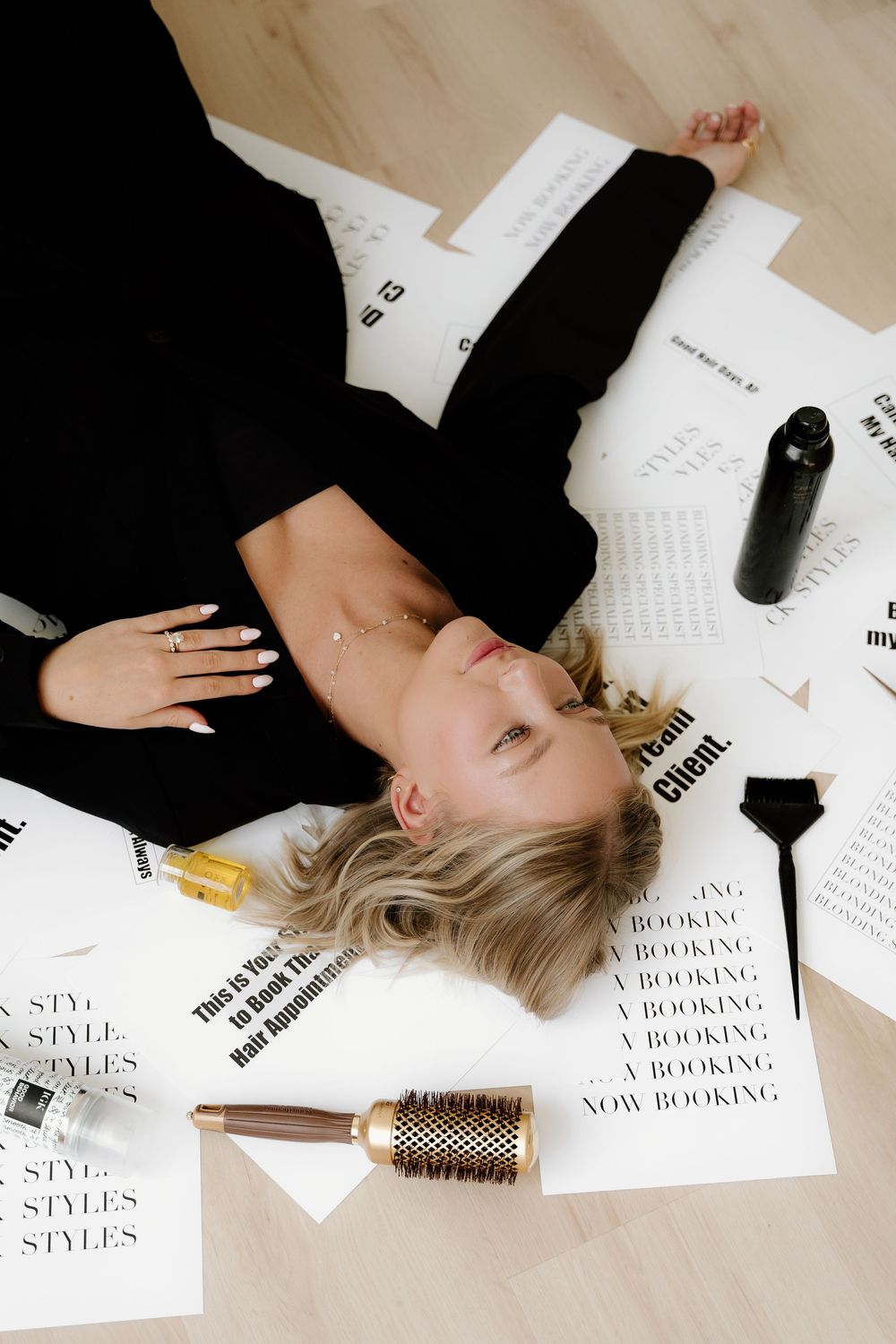 Creative photo shoot setup with hair styling tools and branding materials scattered on floor.