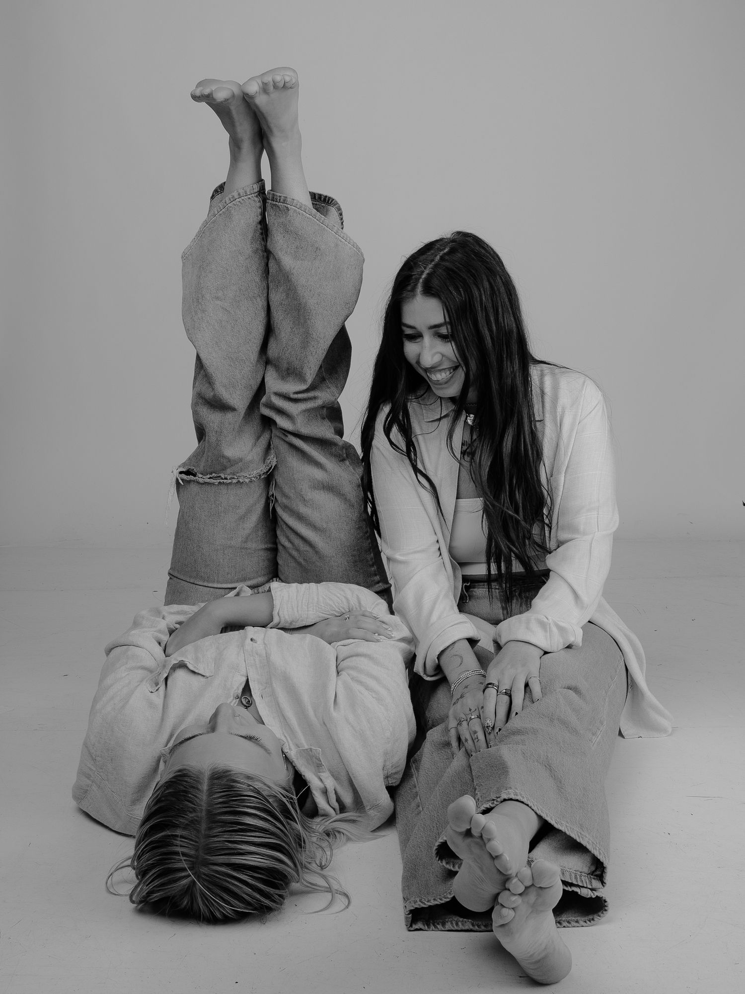 Four black and white artistic photographs show a couple sitting and laying together in casual poses on the floor.