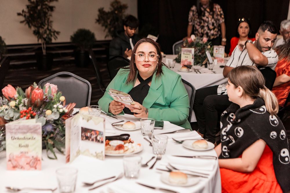 People seated at an elegant banquet table with floral centerpieces enjoying a meal at a social gathering.