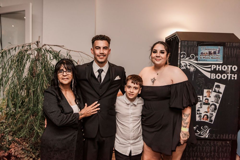 Wedding guests smile and pose together for candid photo booth style snapshots at an indoor reception celebration.