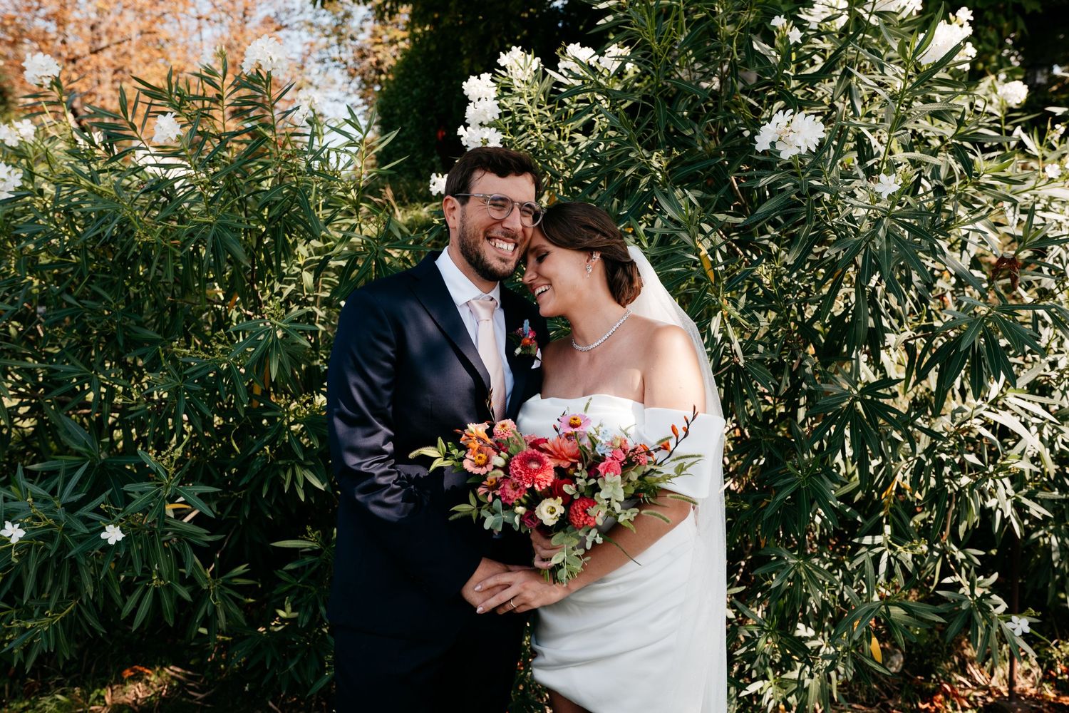 Happy couple shares romantic moment in garden setting with glowing autumn colors and white flowers.