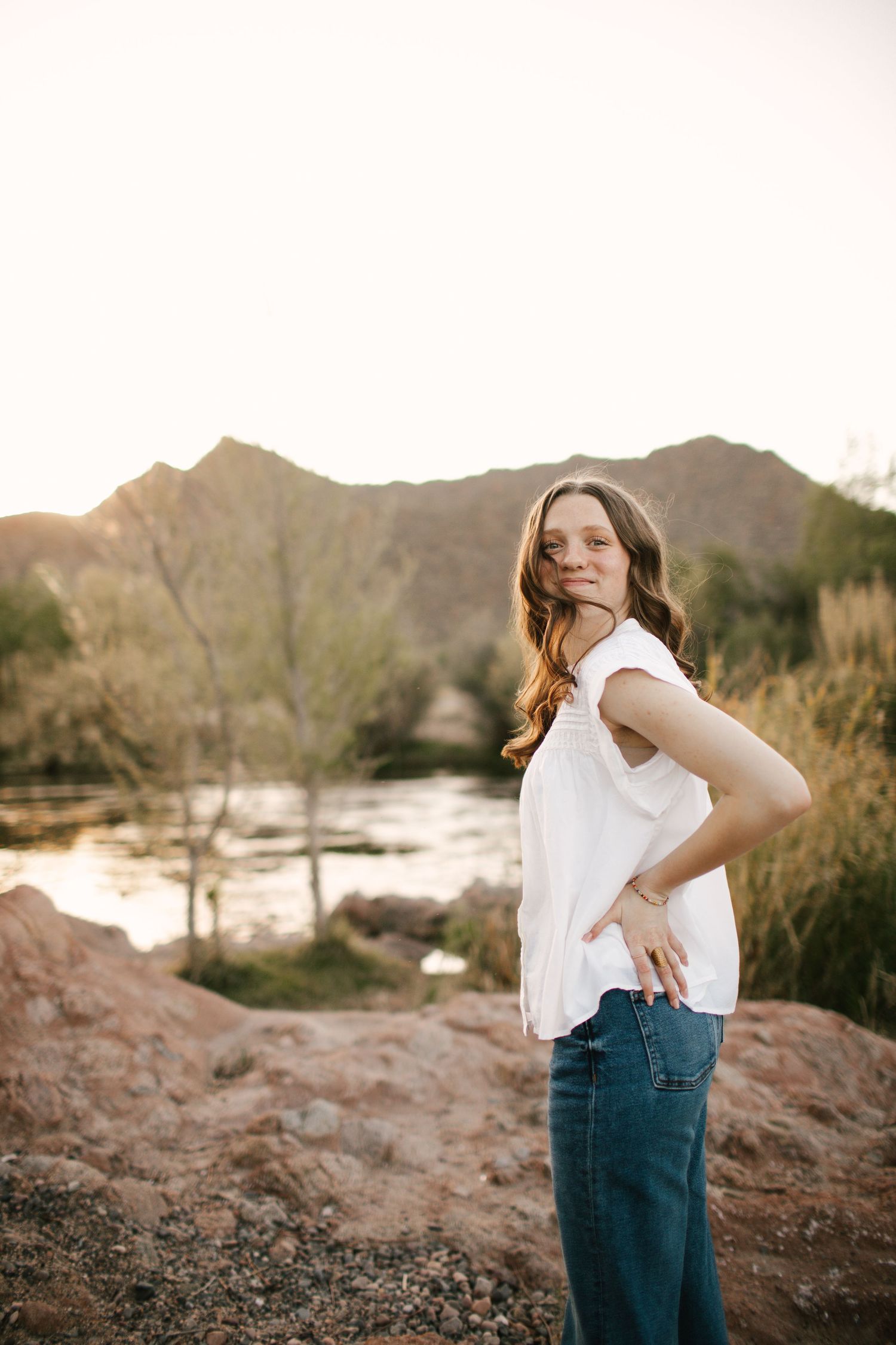 Senior girl looking over shoulder in front of lake and mountain background