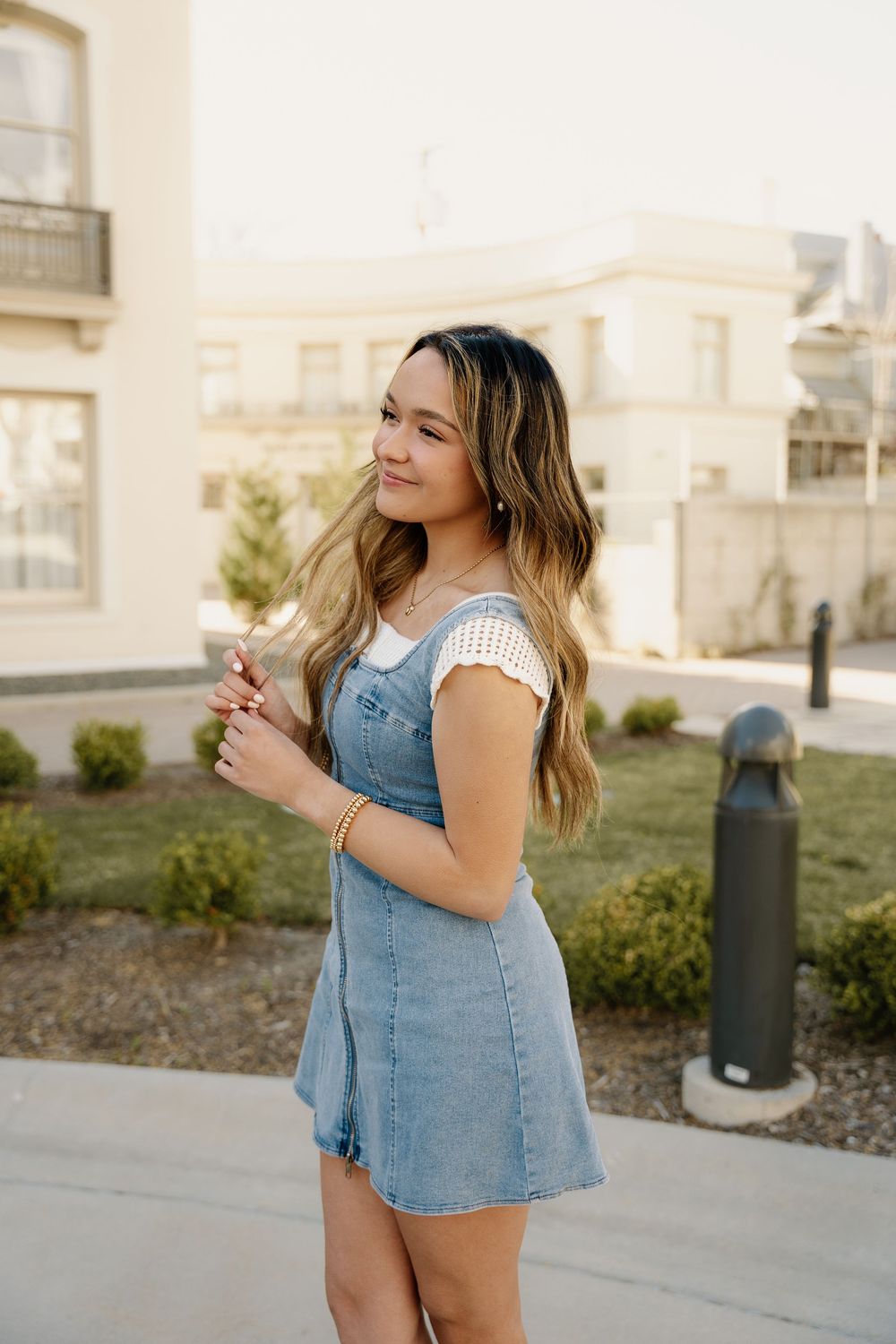 A warm sunset portrait in a denim dress against classic architecture.