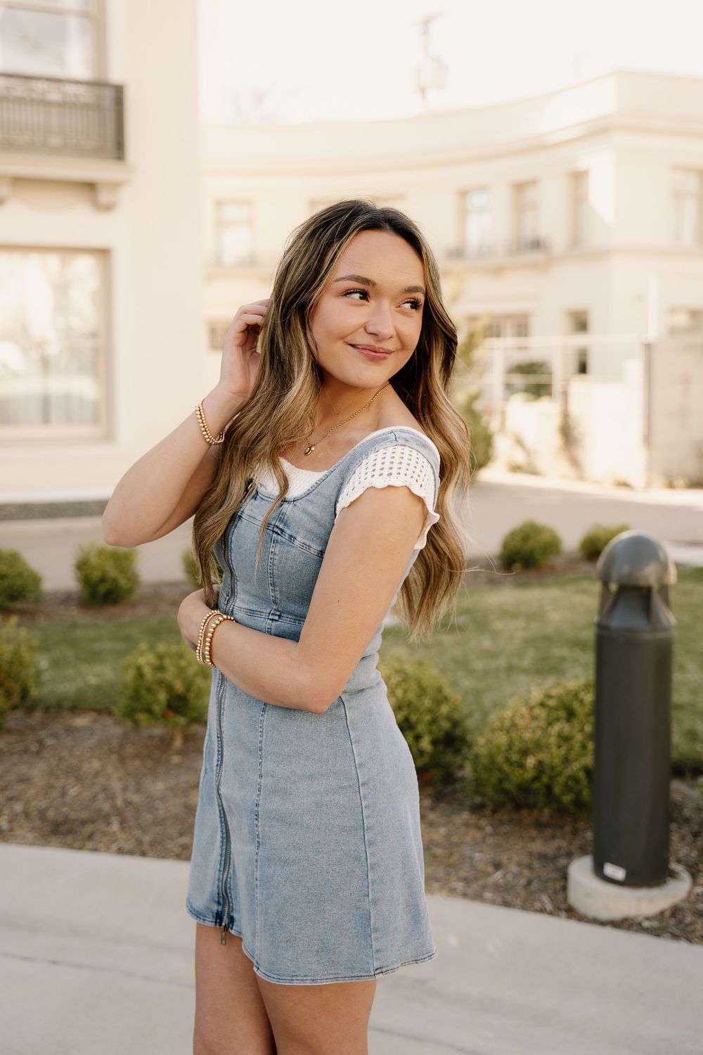 A sunny outdoor portrait in a denim dress with white lace details.