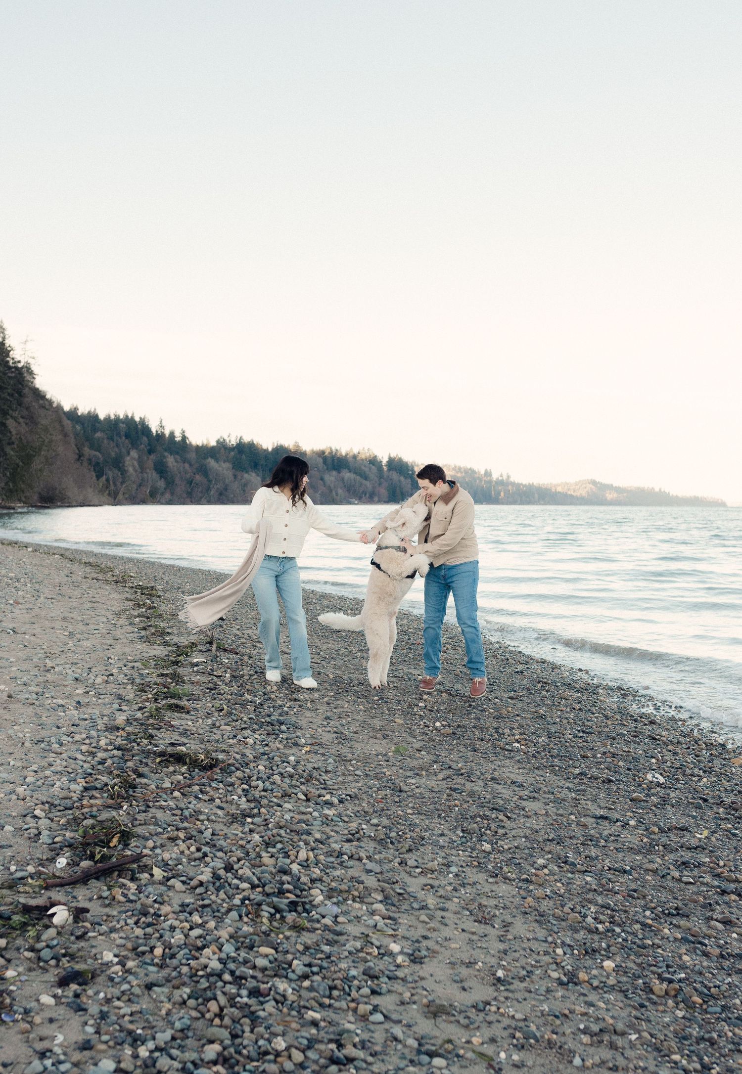 Three people walking and enjoying a casual stroll along a rocky Pacific Northwest beach at dusk.