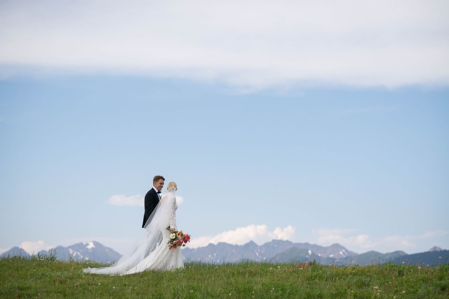 Wedding portraits taken on a hilltop with dramatic mountain vistas.