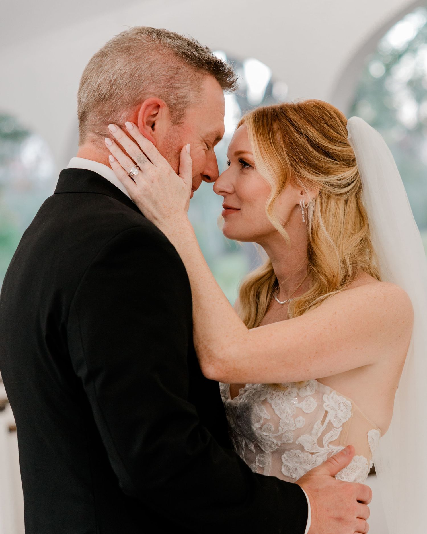 A tender moment between newlyweds as the bride caresses her groom's face during an intimate wedding portrait.