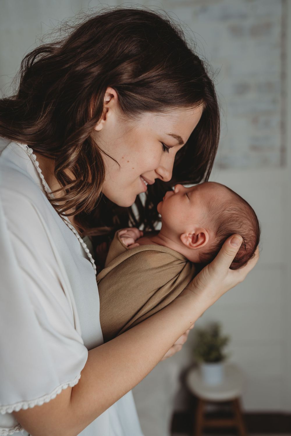 An intimate portrait of mother and baby sharing a loving moment in white attire.