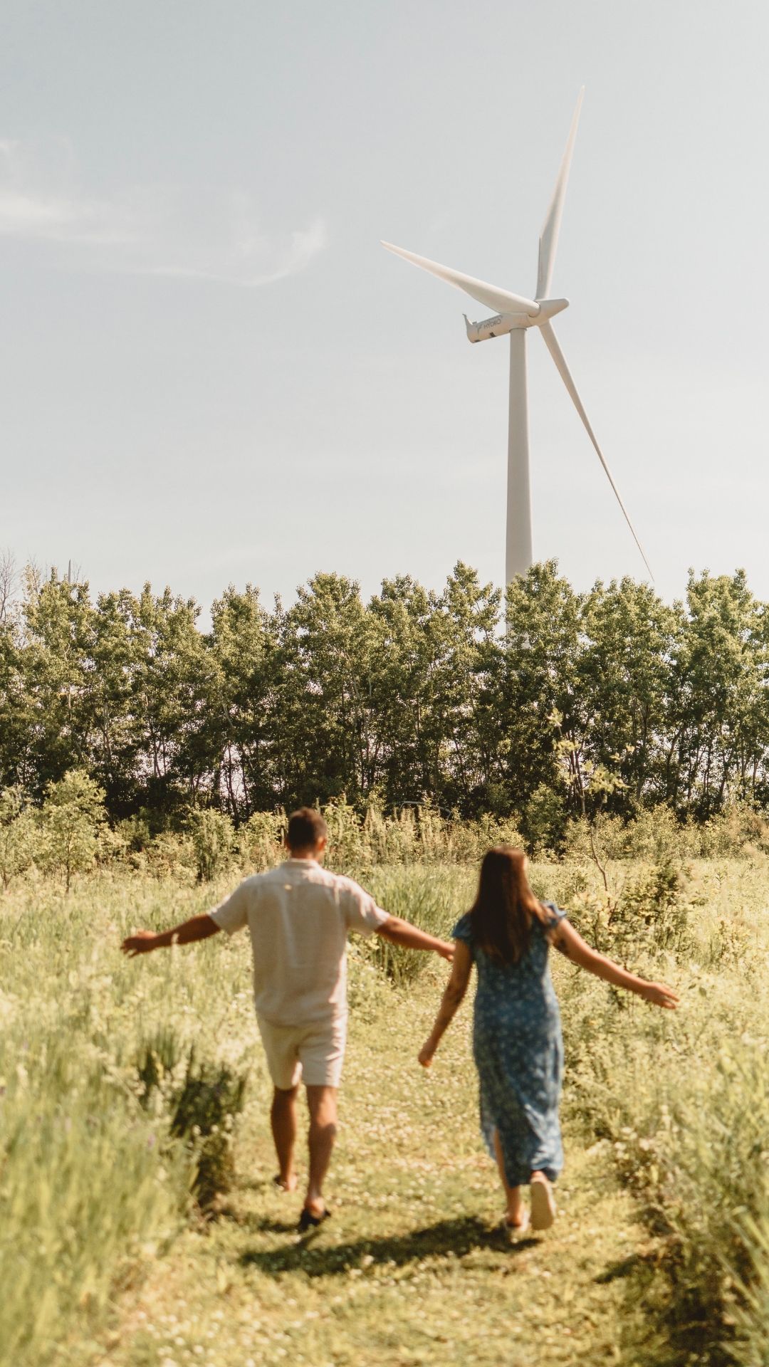 couple run towards a windmill at a conservation area on wolfe island, near kingston ontario. things to do photo shoot