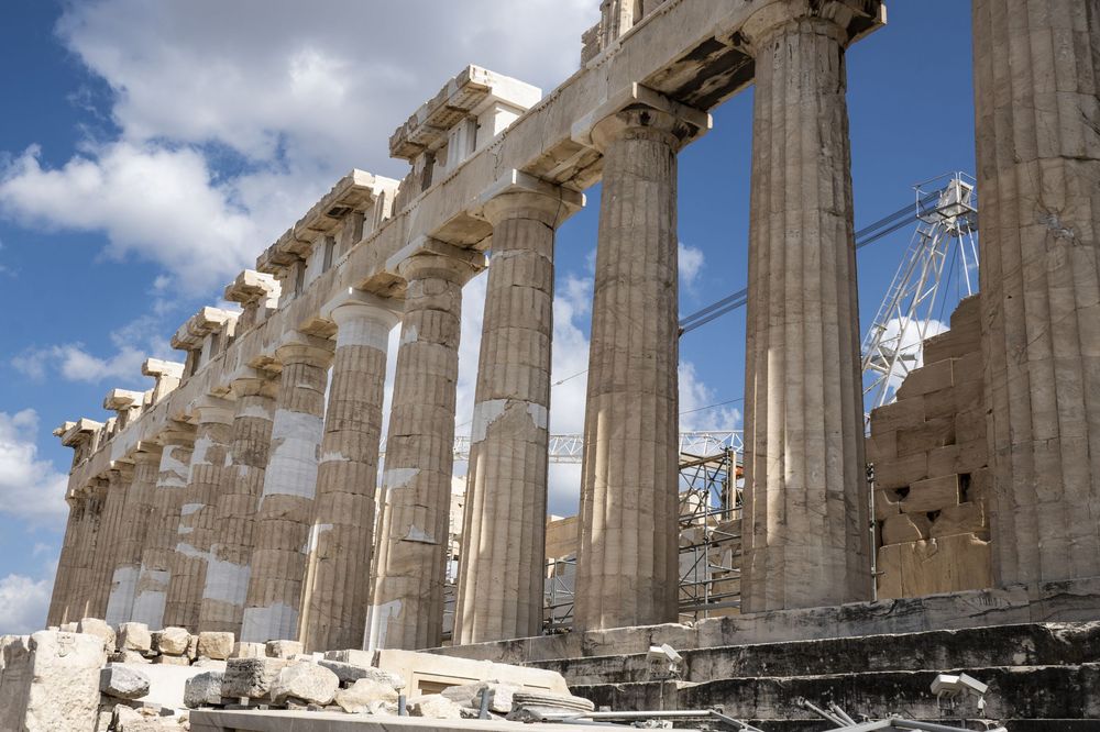 Ancient Greek temple ruins with tall Doric columns against a blue sky at the Acropolis in Athens.