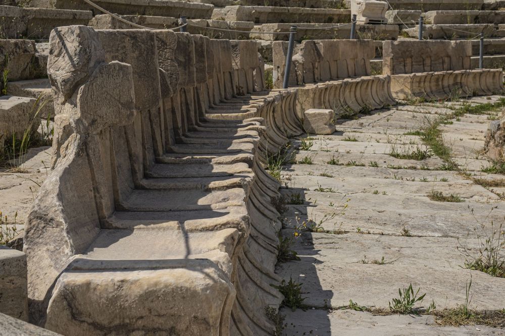 Ancient stone columns line a path at the ruins of Ephesus in Turkey, casting dramatic shadows in the afternoon sun.