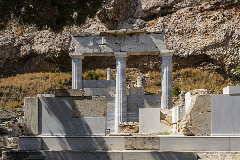 A series of concrete support columns under construction along a rocky cliff face with metal reinforcement bars visible.