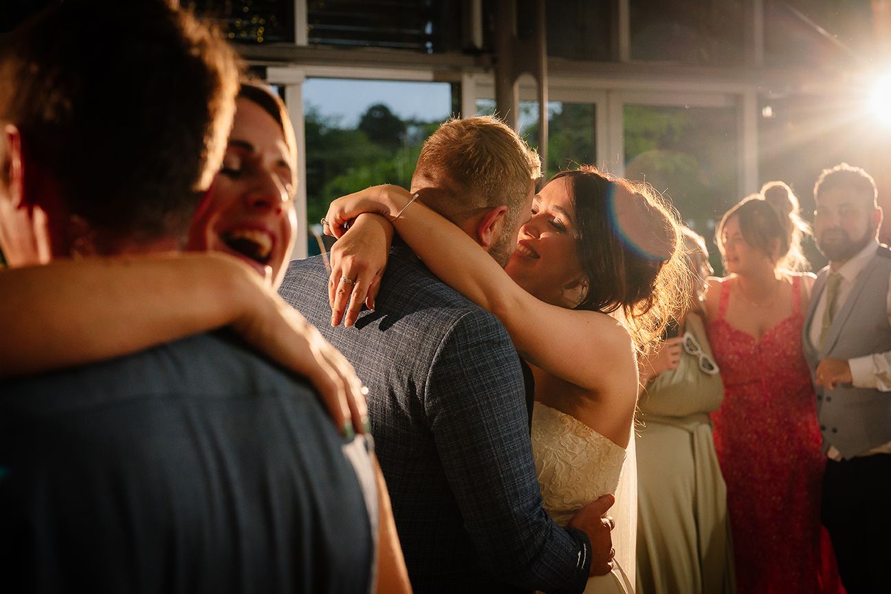 Couples dancing intimately at a wedding reception with warm lighting and guests in the background.