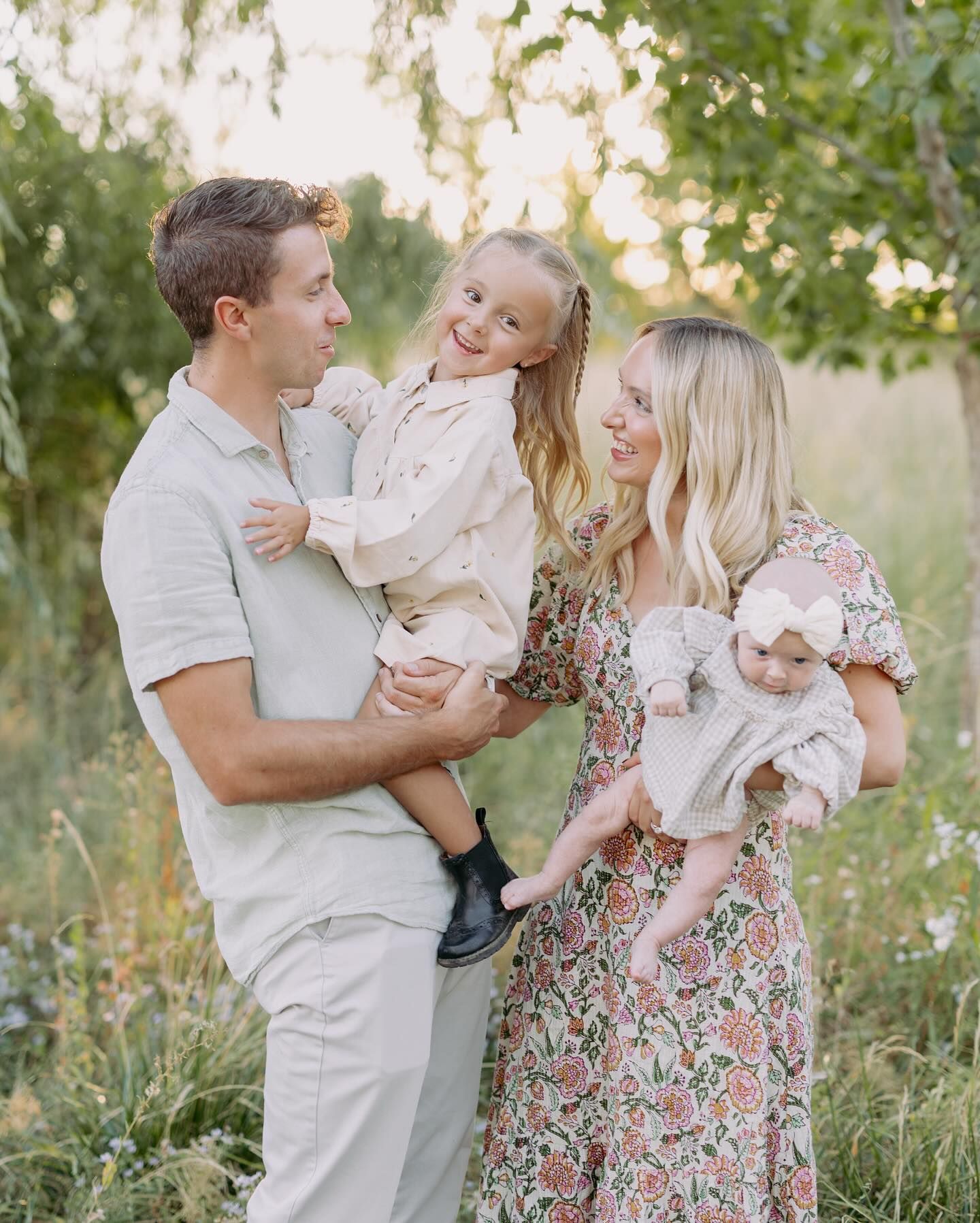 Family shares joyful moments together outdoors in coordinated white and floral outfits during summer evening.