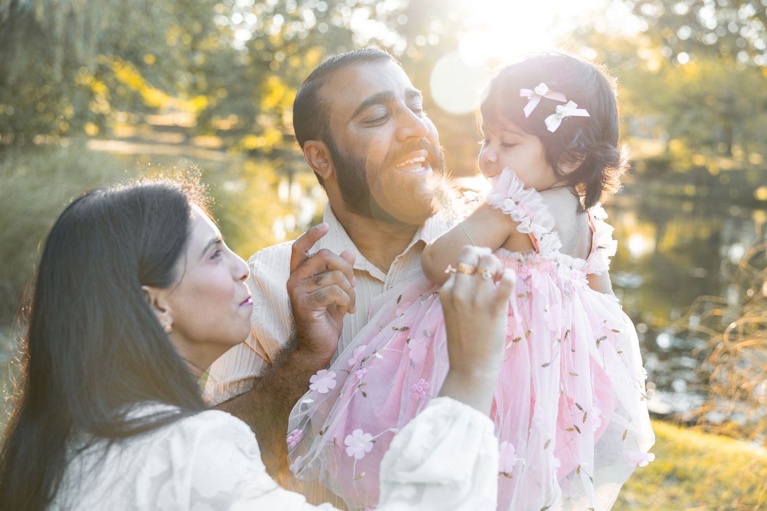 Family enjoying tender moments together outdoors during golden hour sunset in a park setting.