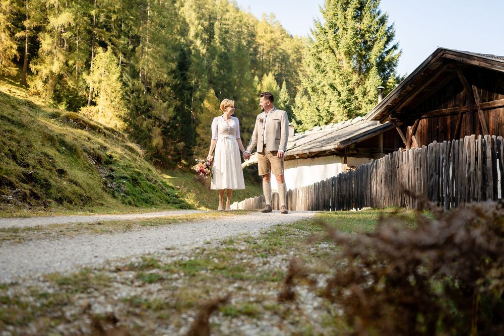 Brautpaar spaziert an einem urigen Tiroler Heustadel vorbei durch das herbstliche Stubaital