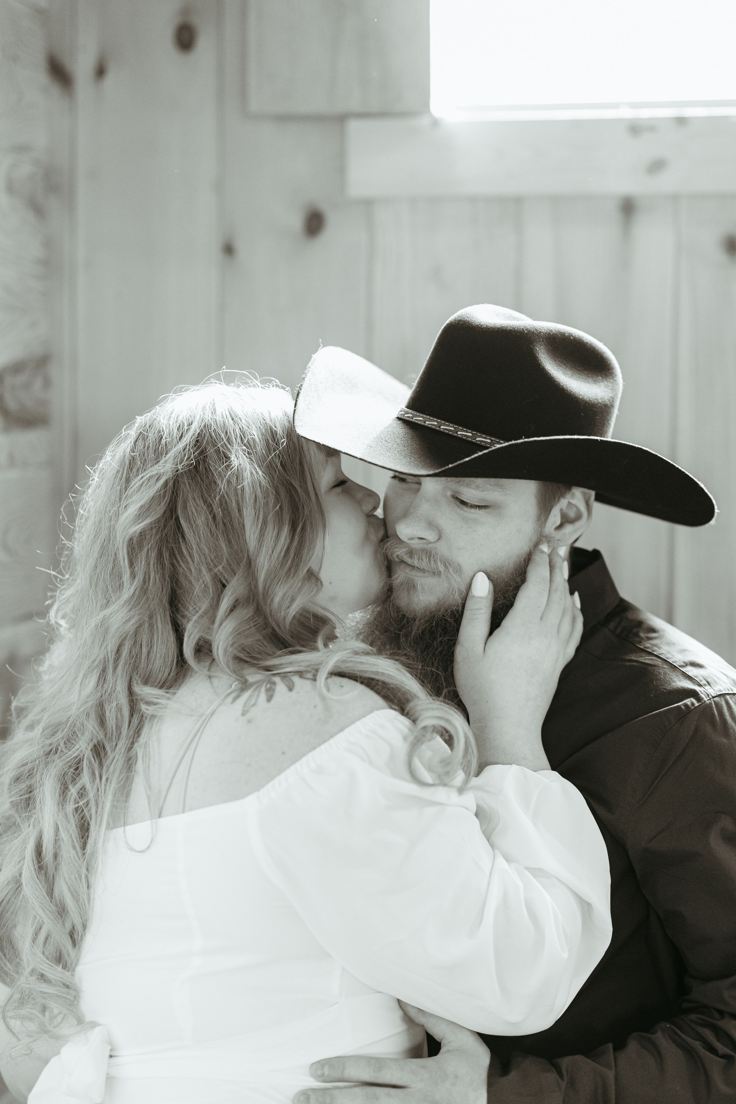 Black and white photo series capturing intimate romantic moments between a couple at engagement session barn location.