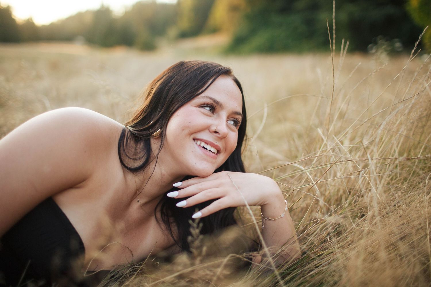Everett WA fun Senior photography: A high school senior girl lays in the tall grass during her senior portrait session