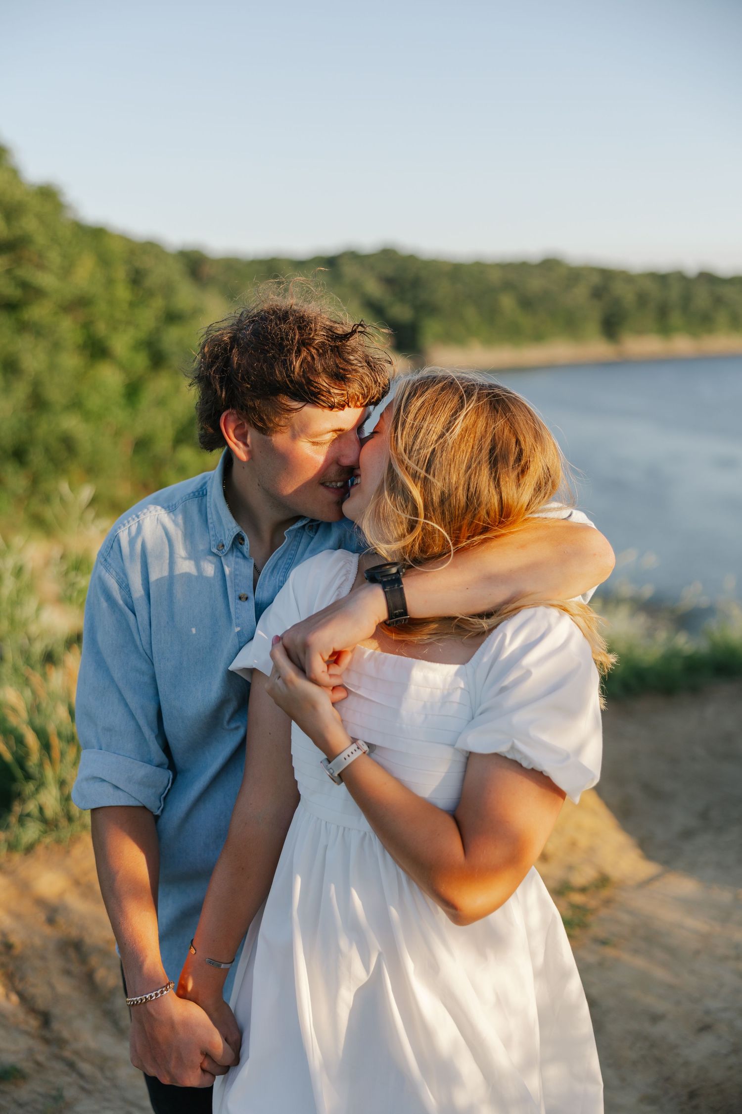 A couple shares a romantic moment in a sunlit meadow during golden hour.