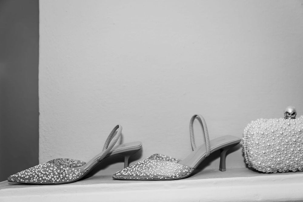A row of elegant bridal shoes with sparkly details displayed against a light gray background.