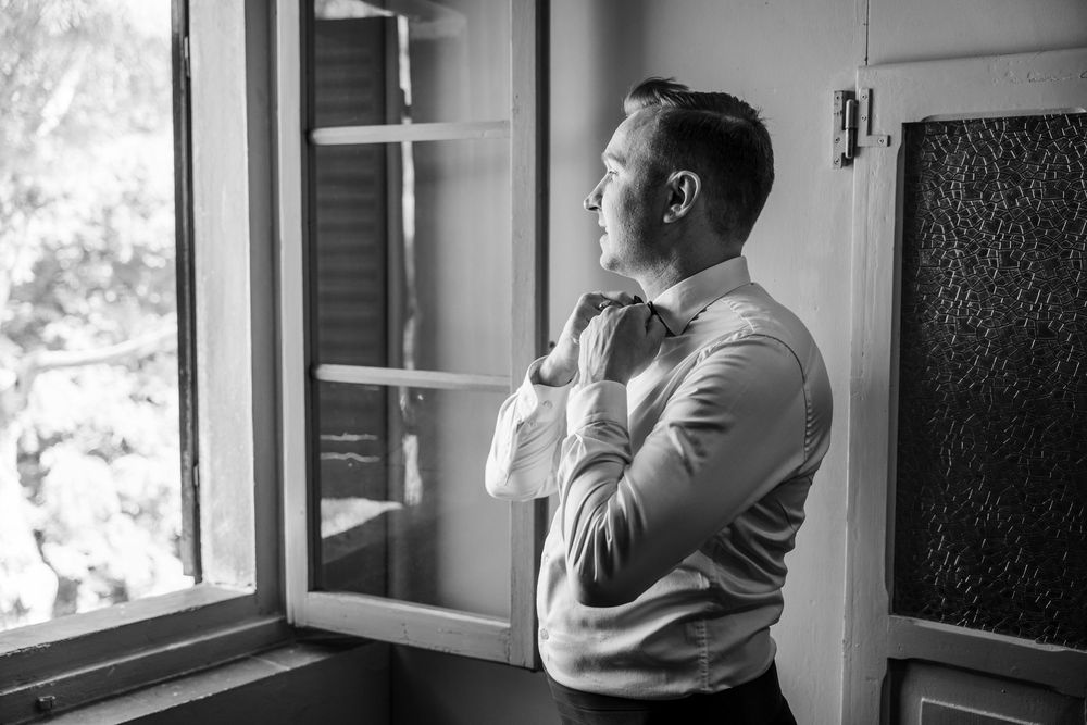 Black and white photo showing contemplative moments before the ceremony near a window.