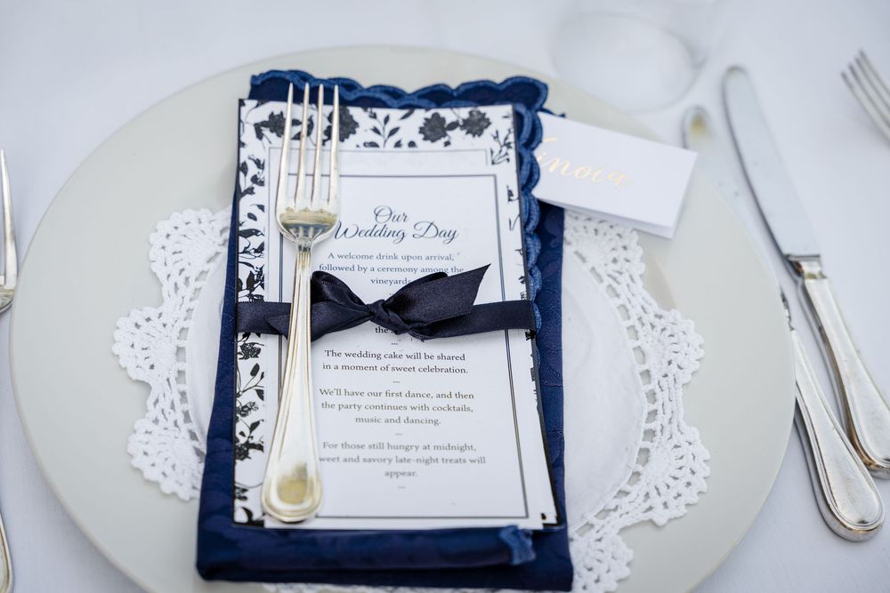 Elegant navy blue and white wedding invitations with lace details and ribbon accents displayed on white background.