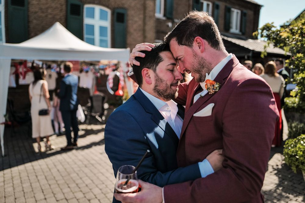 Hochzeit am Baumannshof: Zwei Gäste umarmen sich herzlich während des Sektempfangs im Freien. Authentische Hochzeitsreportage von Fabio Marr