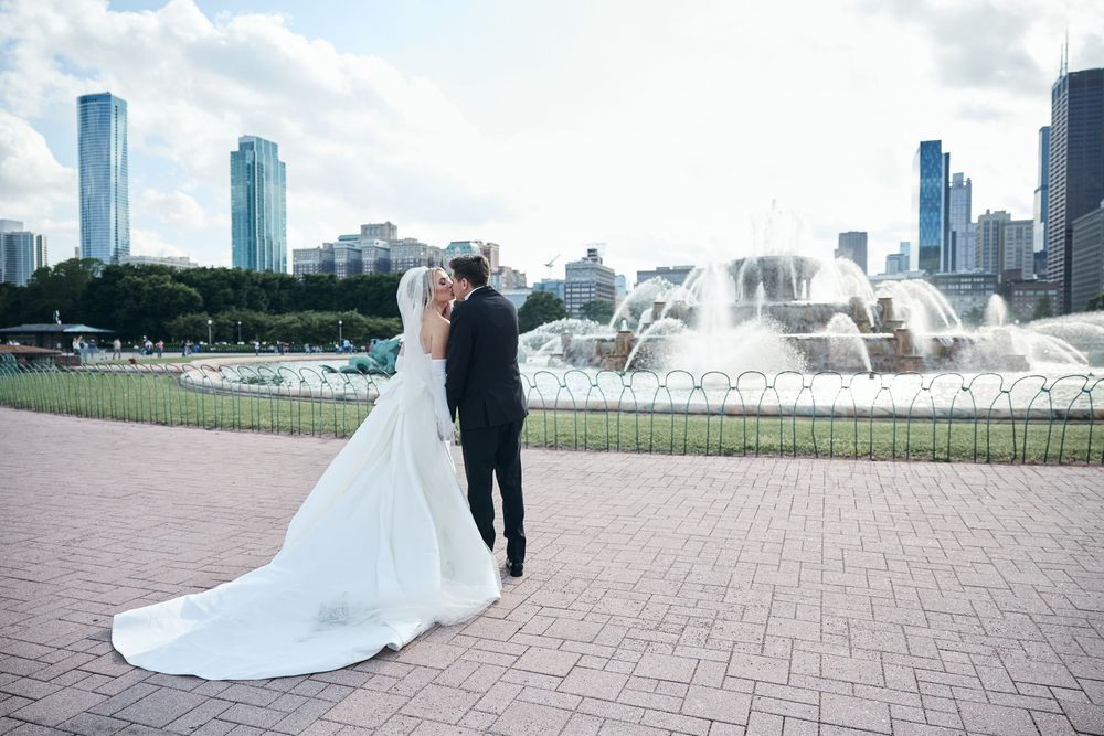 Couple poses near Buckingham Fountain in Chicago with downtown skyline and Lake Michigan in the background.