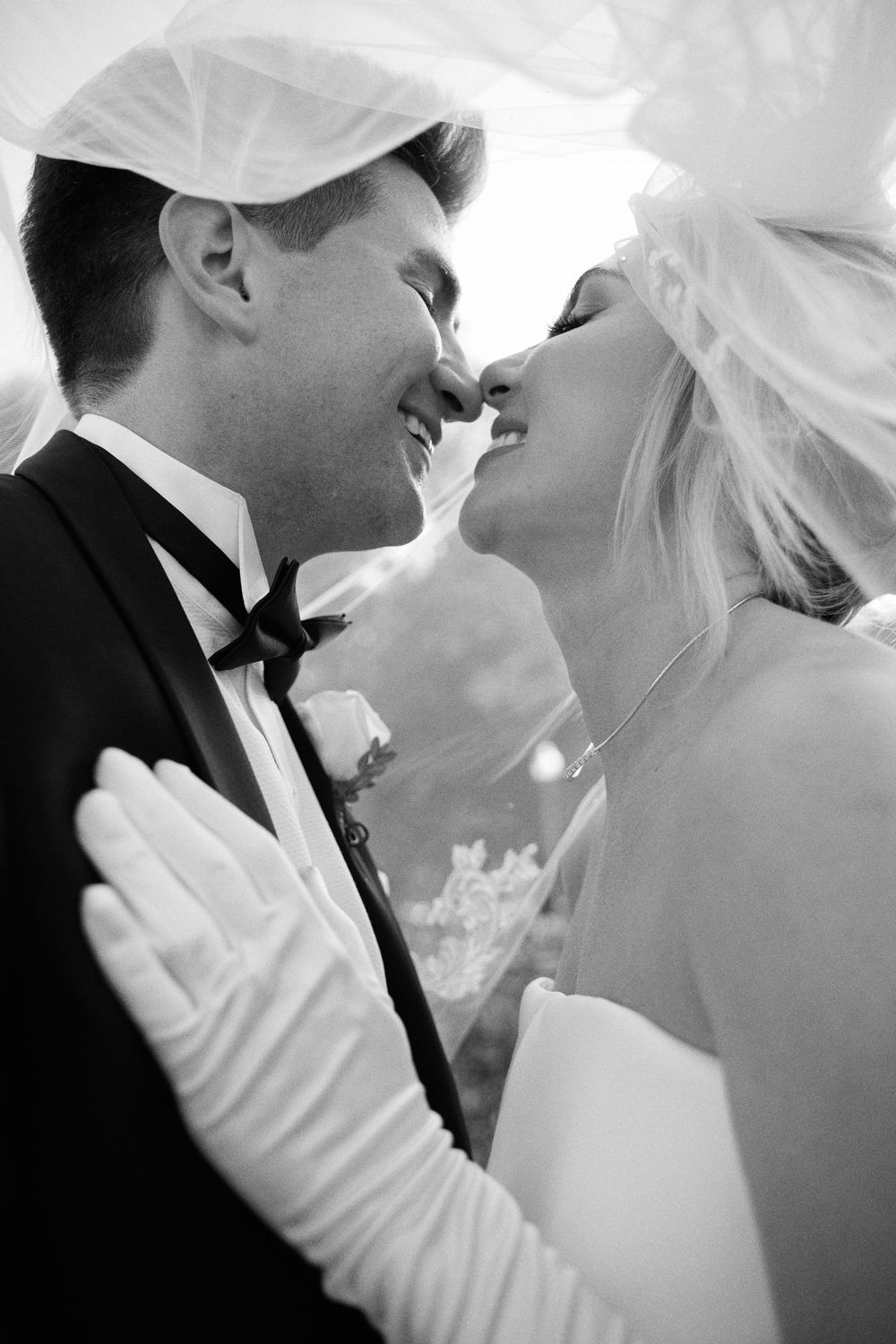 A romantic black and white photo series showing tender moments between a bride and groom under her flowing veil.